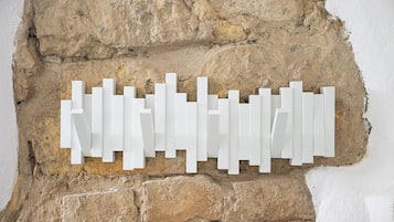 Eine weiße, geometrische Wanddekoration vor einer strukturierten Steinwand.