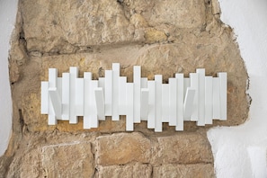 Eine weiße, geometrische Wanddekoration vor einer strukturierten Steinwand.