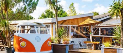 Una furgoneta VW transformada en restaurante con terraza y una cubierta de madera.