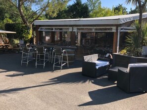 An outdoor seating area with tables and chairs, a covered patio, and a pool. - Mobile home with AC & pets - 4 guests (Grayan-et-l'Hôpital)