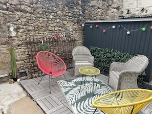 A patio area with wicker furniture, a stone wall, and a decorative string of lights. - "Chez Laurette"—a vacation rental for 8 people between Beauval, Chambord, and Cheverny (Les Montils)