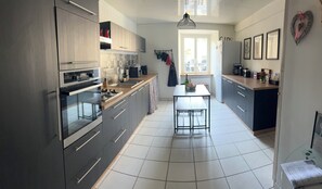 A modern kitchen with a central island, stainless steel appliances, and a view to the dining area. - "Chez Laurette"—a vacation rental for 8 people between Beauval, Chambord, and Cheverny (Les Montils)