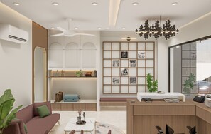 A modern hotel lobby with a reception desk, seating area, and a wall with framed pictures. - Hotel Parshwa (Ujjain)