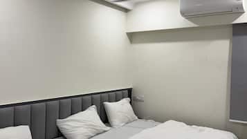 Quarto de hotel com cama, ventoinha no teto e ar condicionado.