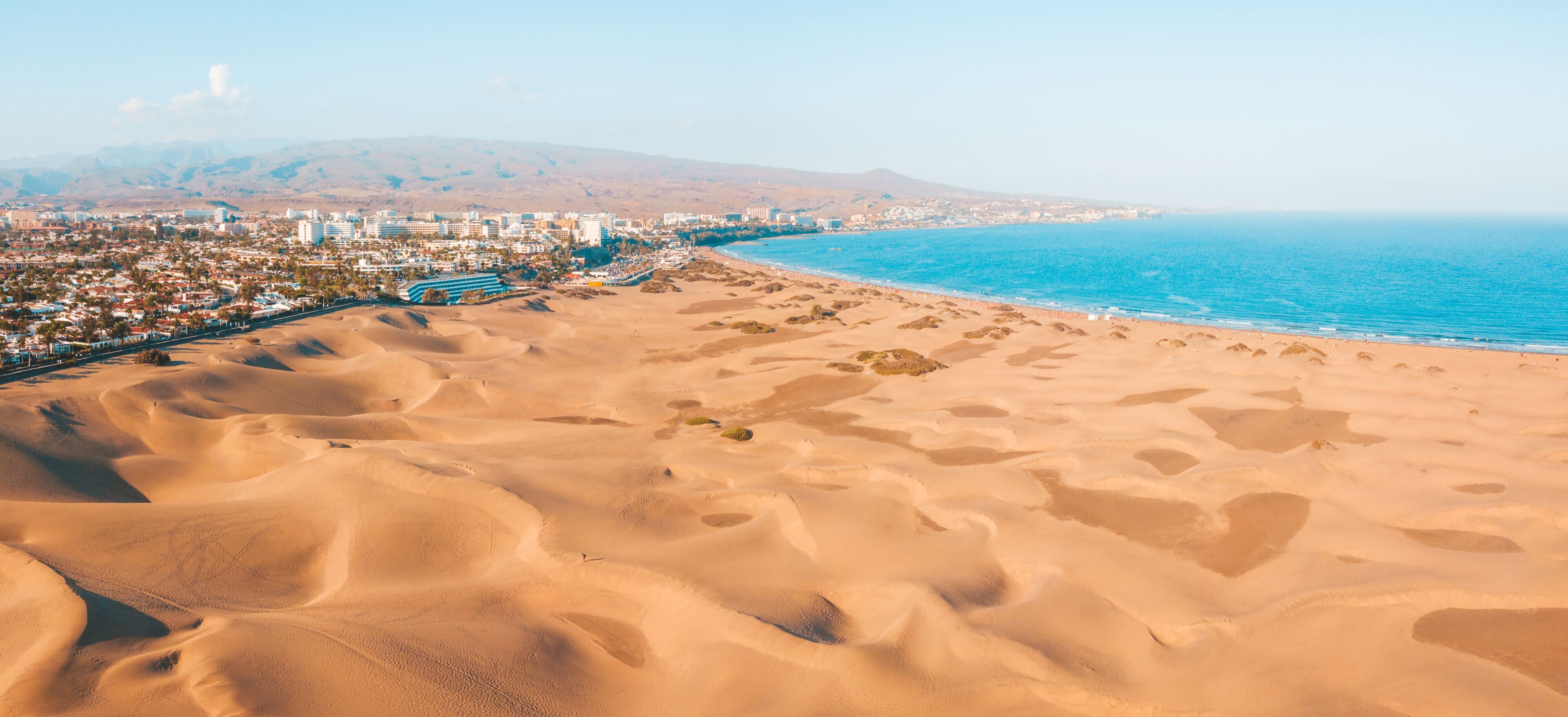 Un paysage urbain côtier avec une plage de sable et une vue dégagée sur l’océan.