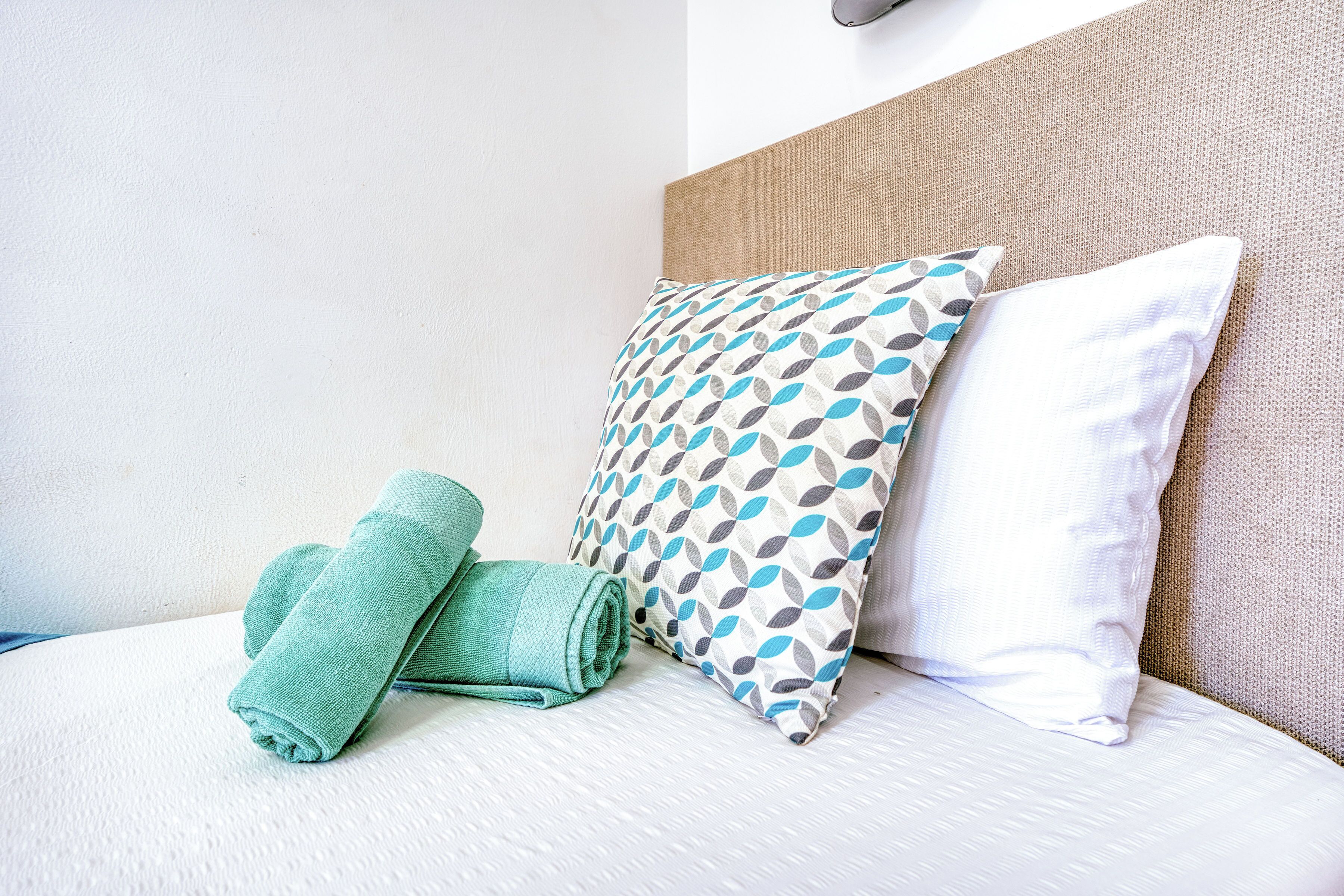 A neatly made bed with two pillows and a folded towel.