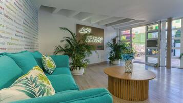 Ein modernes Interieur mit einem türkisfarbenen Sofa, einem Holztisch und Blumentöpfen.