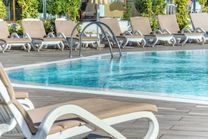 Un área junto a la piscina con sillones de descanso y una piscina.