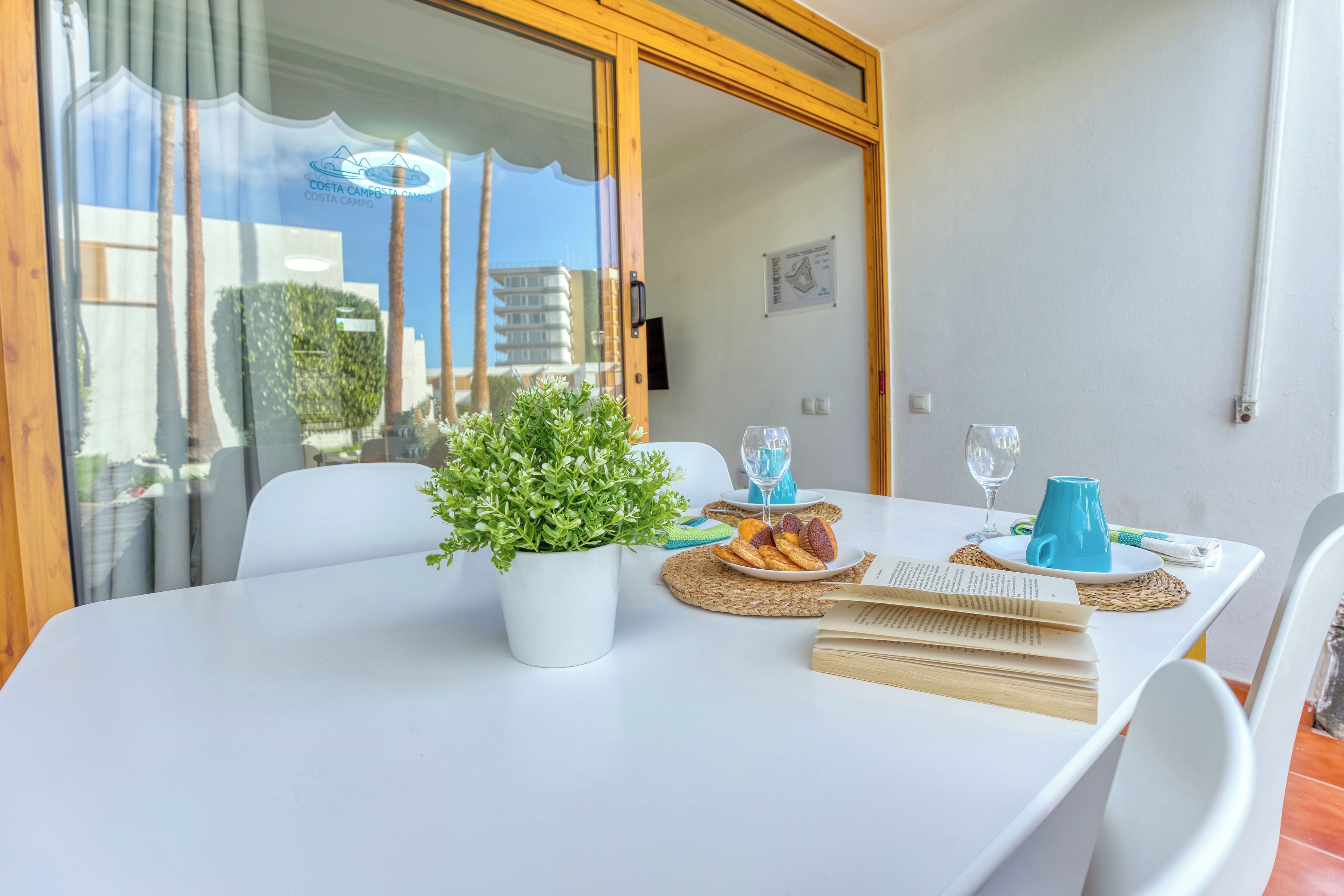 Una mesa de comedor con una planta en maceta, un plato de comida y un libro.