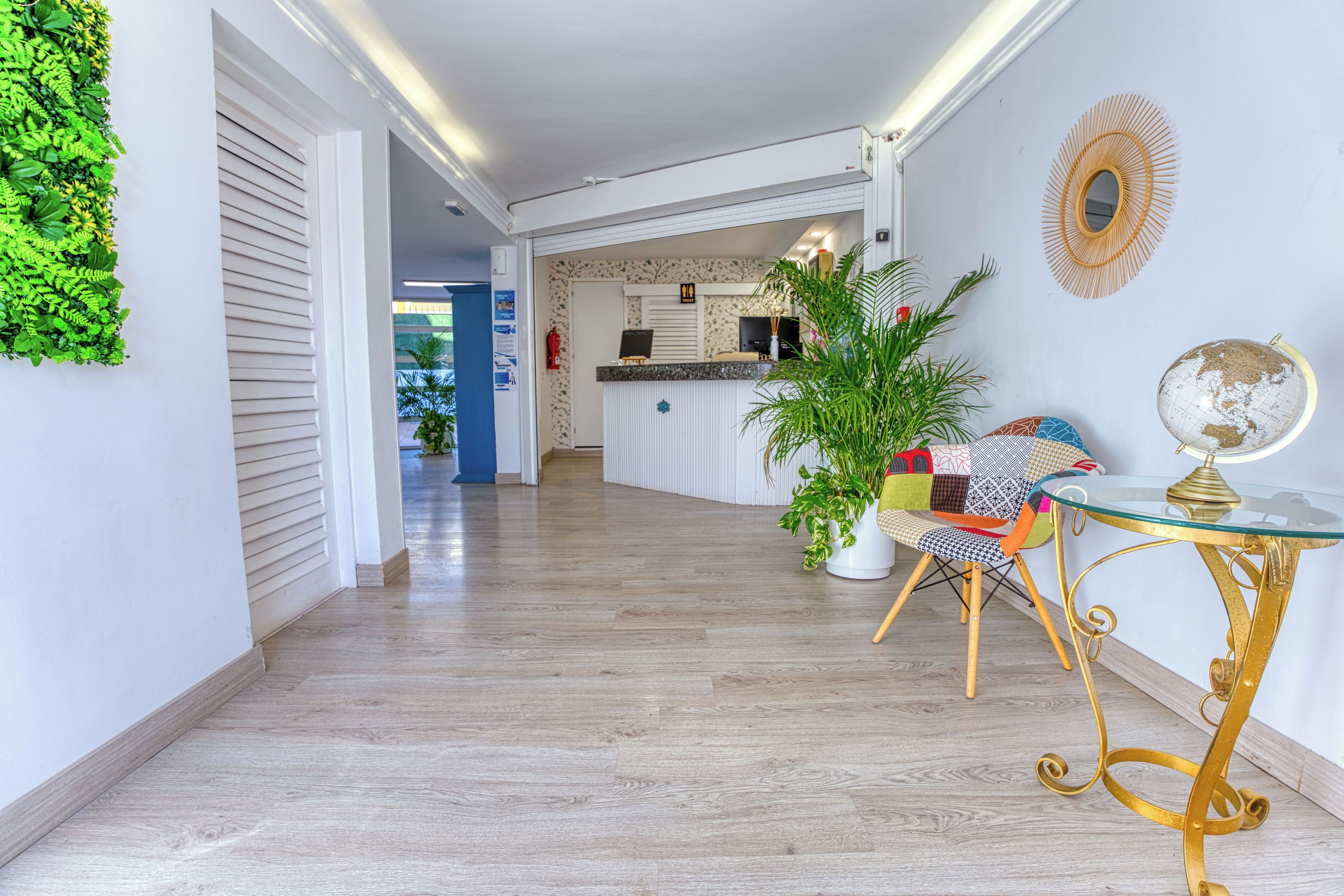 Een modern interieur met een houten vloer, een receptiebalie, een plant, een wereldbol en een gestreept stoel.