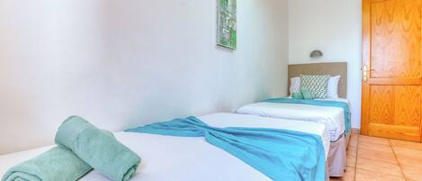 A hotel room with two beds, a wooden door, and a wall-mounted light fixture.