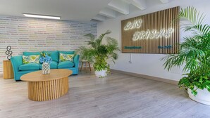 A modern interior with a teal sofa, a round wooden coffee table, and a wall-mounted sign. - Las Brisas (San Bartolomé de Tirajana)