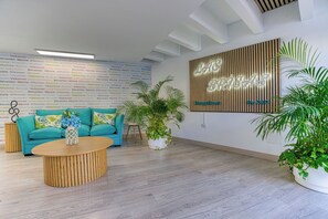 Un intérieur moderne avec un canapé de couleur turquoise, une table basse ronde en bois et un panneau décoratif fixé au mur.