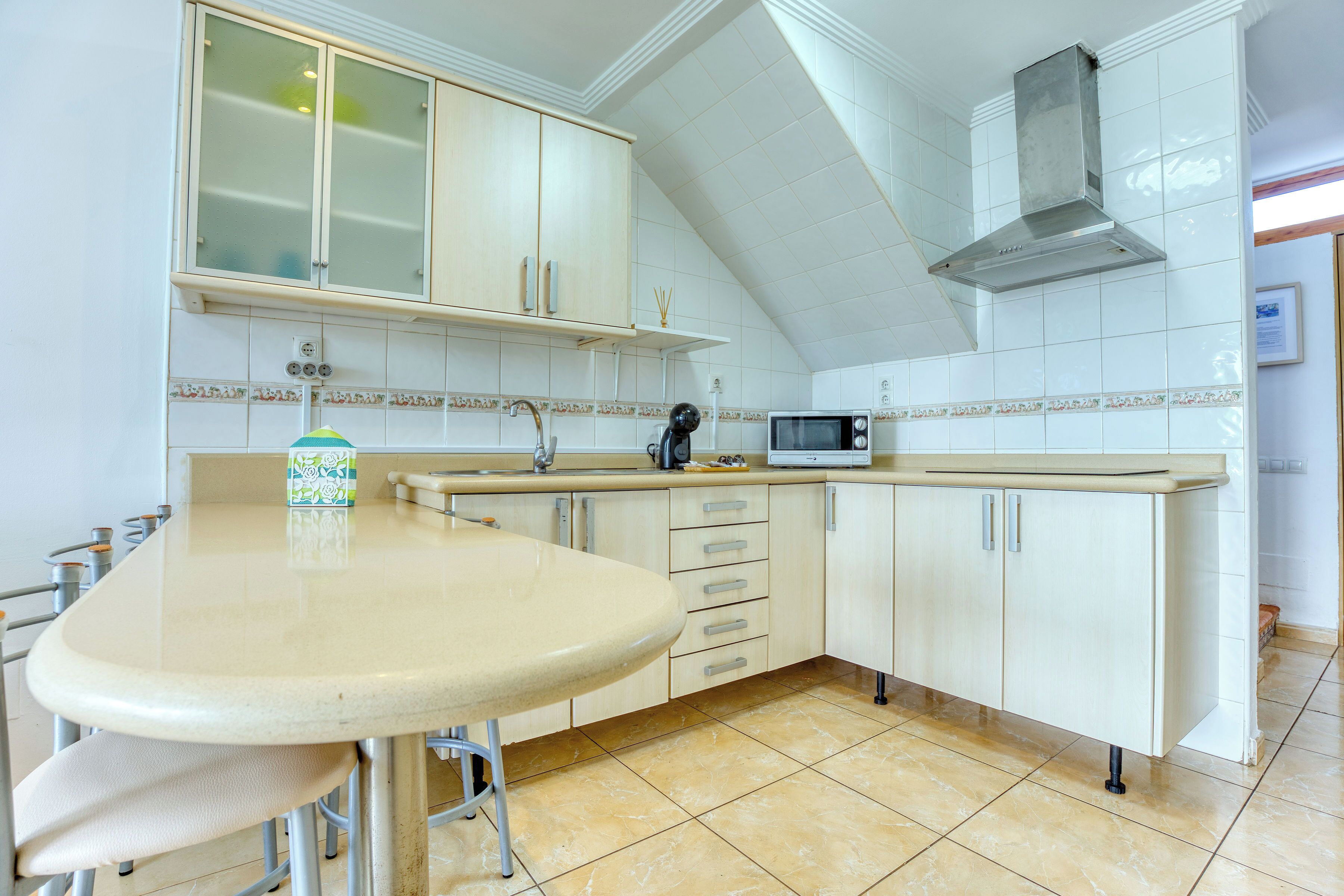 Een keuken met een eethoek, witte kasten, een magnetron en een gasfornuis.