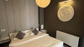 Un dormitorio moderno con una cama grande, una lámpara colgante, una luz de pared y un radiador.