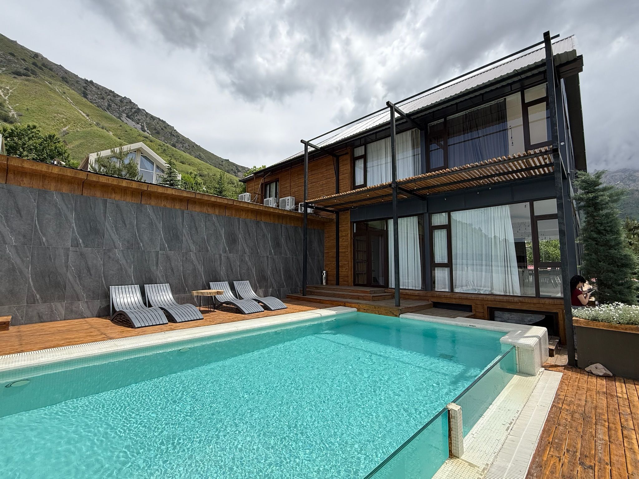 A modern pool area with a clear pool, wooden deck, and lounge chairs.