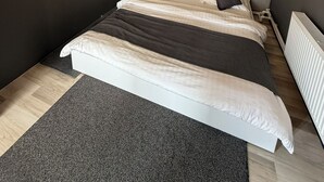 Een moderne slaapkamer met een groot bed, een grijs hoofdbord en een bijzondere houten lamp.