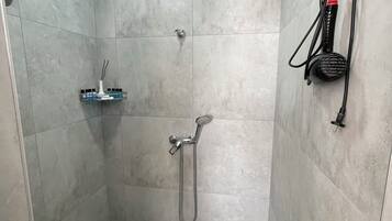 A shower area with a handheld showerhead, a wall-mounted towel rack, and a small shelf with toiletries.