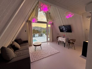 A modern room with a sofa, a small round table, a dining area with chairs, a flat-screen TV, and a large window with curtains. - Balandda Chimgan (Chimgan)