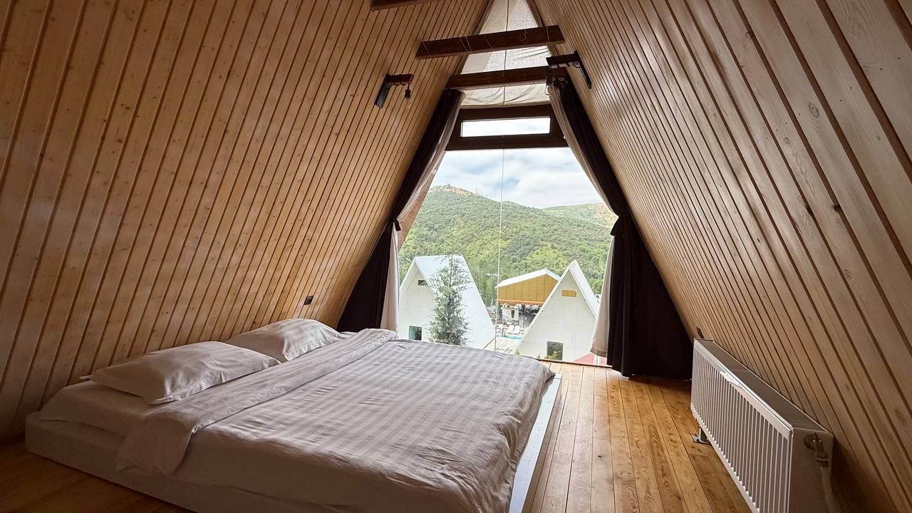Un dormitorio con cama, paredes de madera, una ventana y vistas a casas.