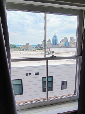 A view through a window of a building with a parking lot and a city skyline in the background. - Edge of Downtown Cincinnati Two Floor Condo (Cincinnati)