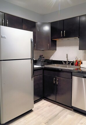 A modern kitchen with stainless steel appliances, dark cabinetry, and a tiled backsplash. - Edge of Downtown Cincinnati Two Floor Condo (Cincinnati)