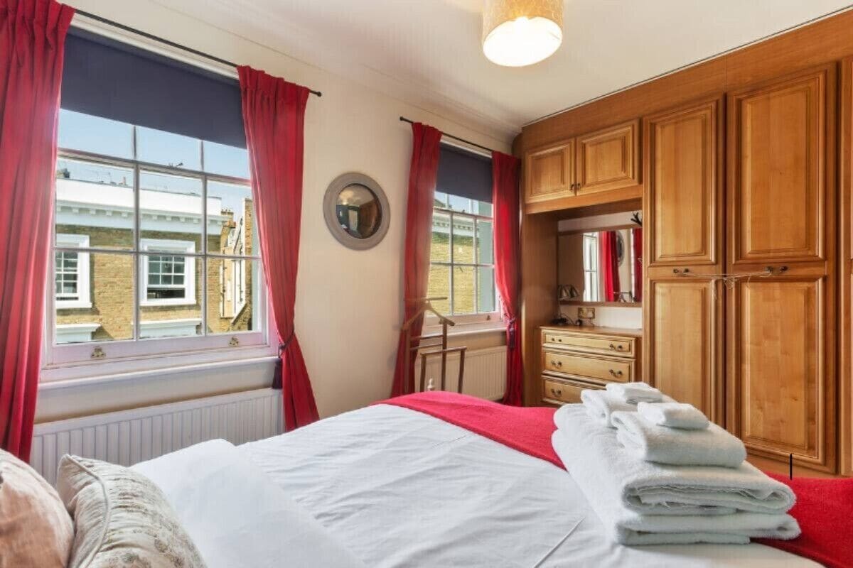 A hotel room with a bed, a dresser, and a window with curtains.