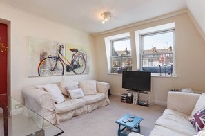 A living room with a sofa, a coffee table, a television, and artwork on the wall. - Maisonette in Central London (London)