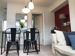 Uma sala de jantar com mesa e cadeiras de vidro, um espelho e vista para o exterior.