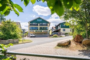 Ein Hotel mit grüner Fassade, mehreren Etagen und einem Parkplatz.