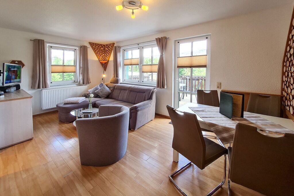 A modern living room with a sofa, a coffee table, and a dining area with chairs and a table.