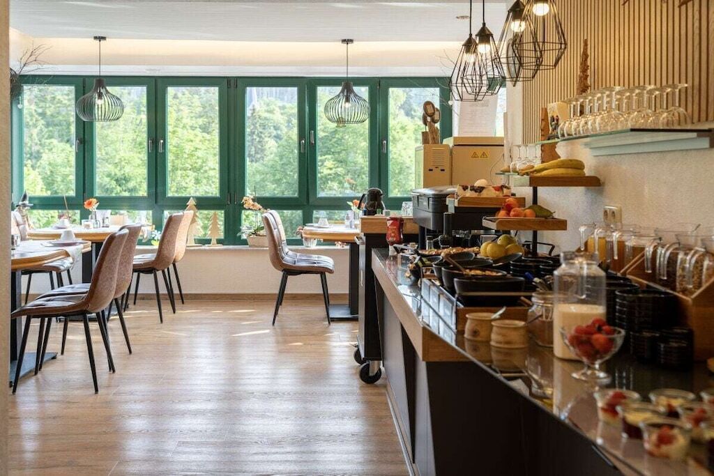 A modern kitchen with a dining area, large windows, and various kitchen appliances.