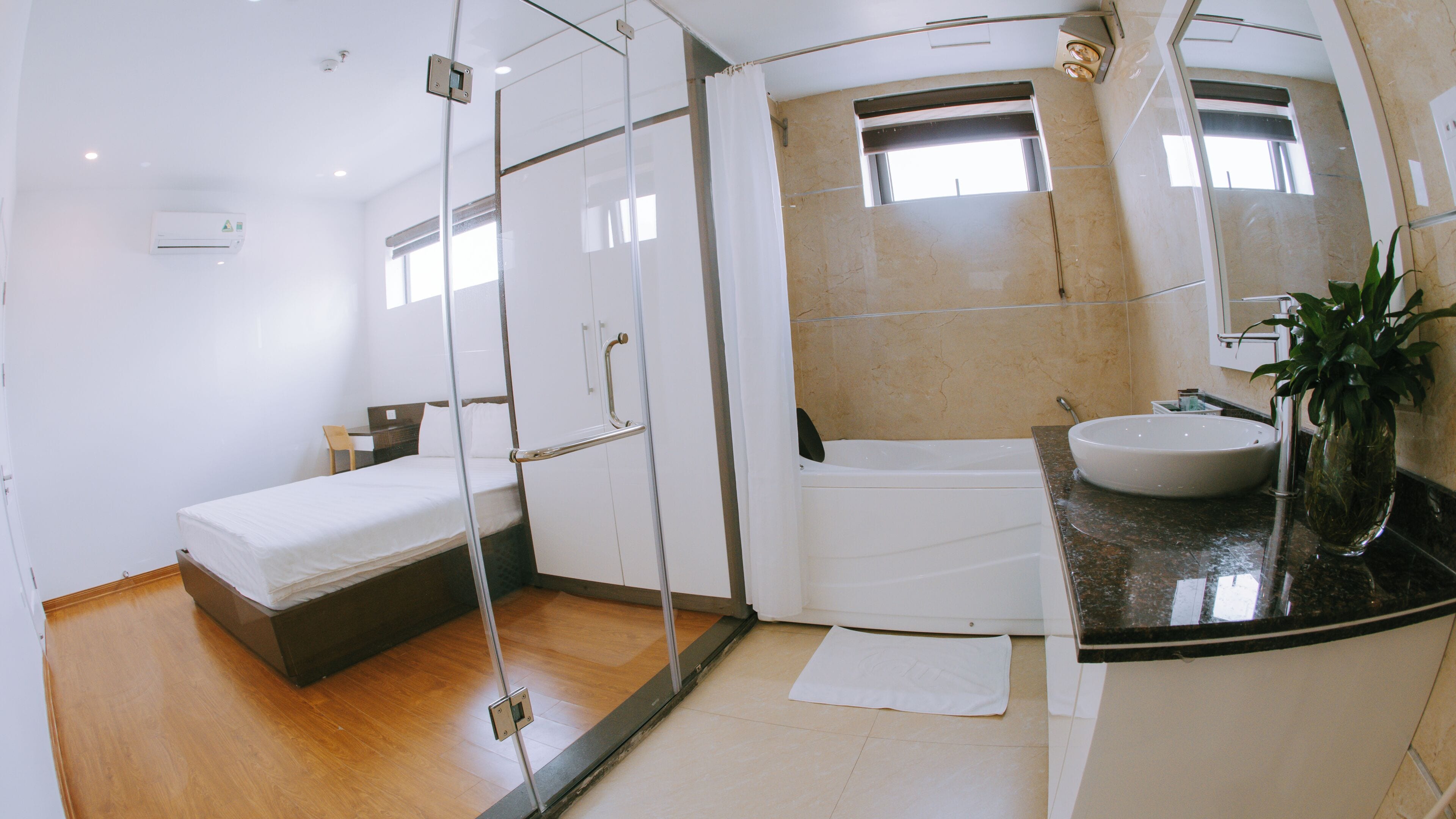 Un baño moderno con cabina de ducha de vidrio, bañera y lavabo con un florero.