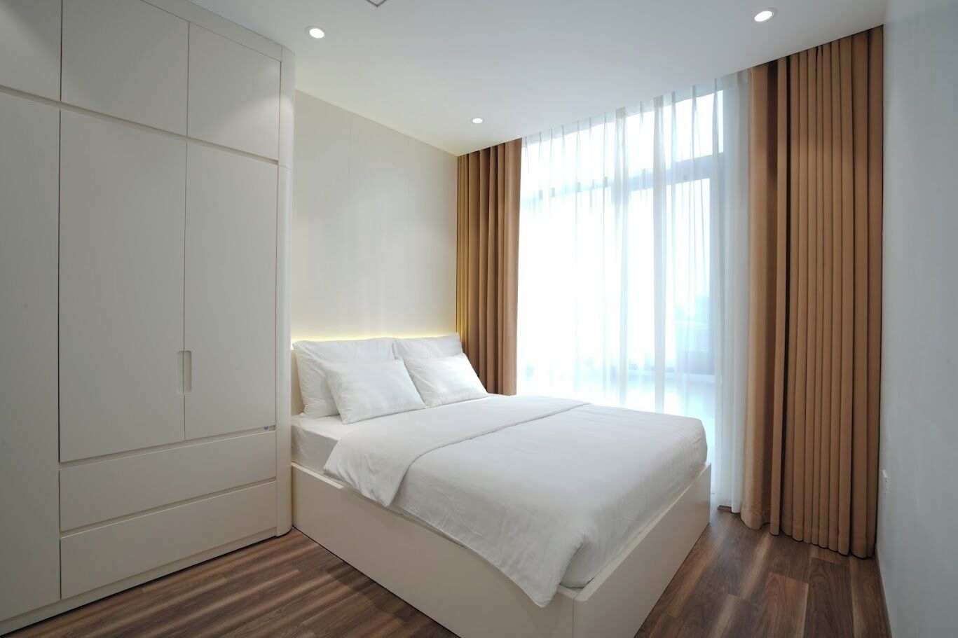 Un dormitorio moderno con cama, armario y un amplio ventanal con cortinas.