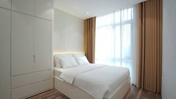 Un dormitorio moderno con cama, armario y un amplio ventanal con cortinas.