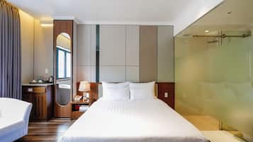 Een hotelkamer met een groot bed, een nachtkastje met lamp, een spiegel en een douchecabine.