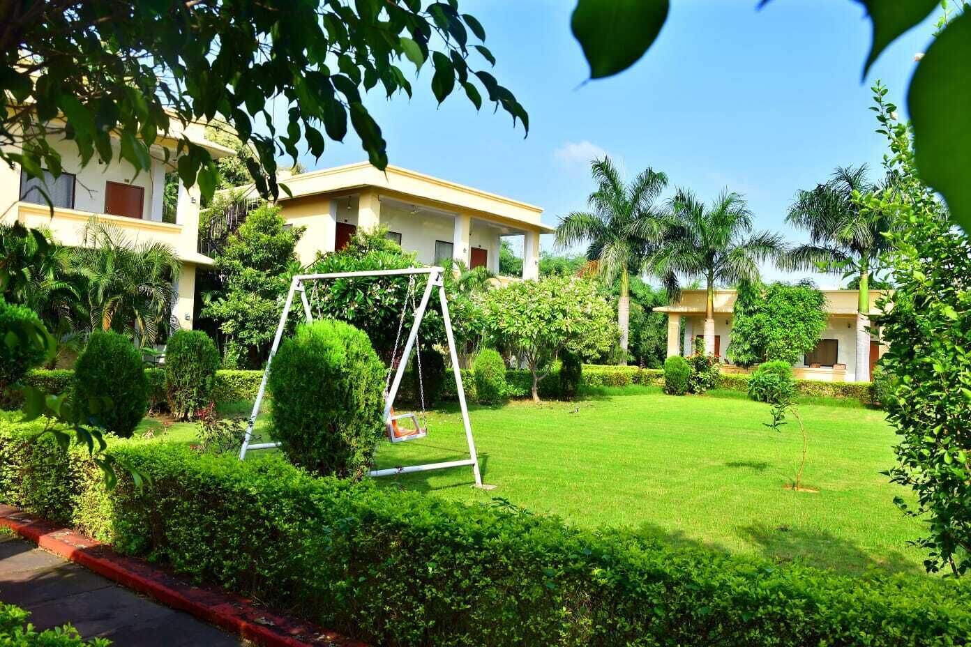 A well-maintained garden with a swing set, neatly trimmed hedges, and a clear sky.