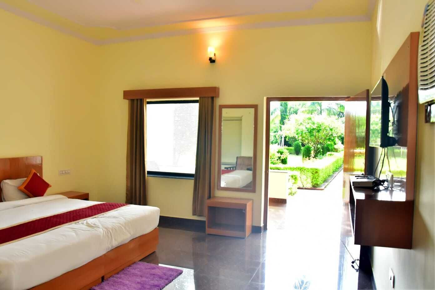 A hotel room with a bed, a desk, a chair, and a view of the garden.