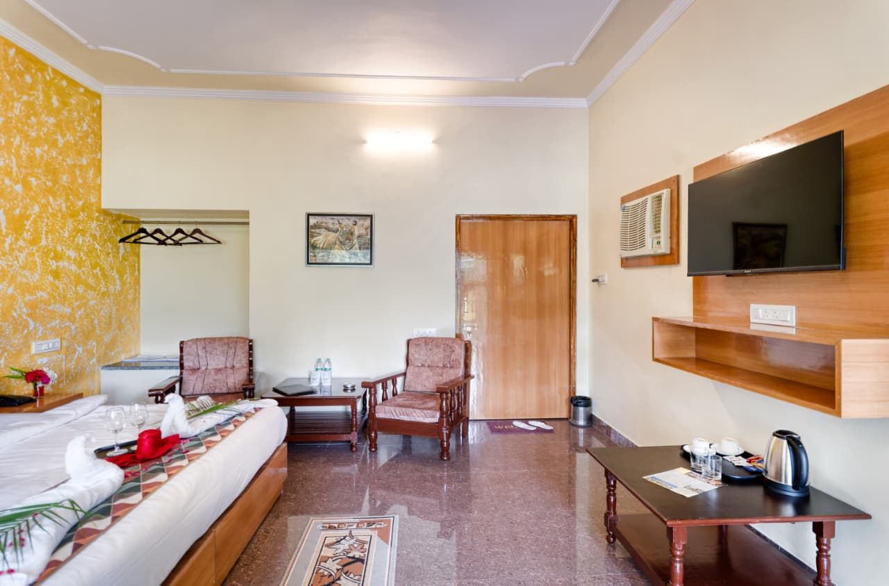 A hotel room with a bed, a desk, a chair, a television, and a wooden shelf.