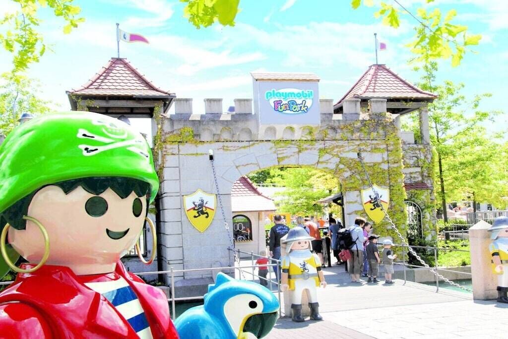Eine burgähnliche Struktur mit einem Schild, auf dem 'PLAYMOBIL! Fun Park' steht, und einer Figur mit grünem Helm.