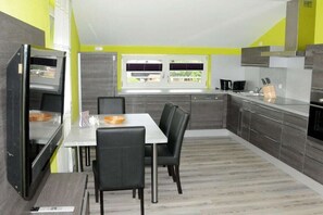 A modern kitchen with a dining area, featuring a refrigerator, microwave, and a window with a view. - Holiday apartment with 2 bedrooms (Oberdachstetten)