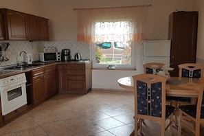 A kitchen with wooden cabinets, a white stove, a microwave, and a dining table with chairs.