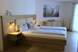 A double bed with two pillows and a headboard, a bedside table with a lamp, and a painting of a deer on the wall. - Brünnstein holiday apartment complex (Oberaudorf)