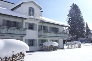 A two-story building with a balcony and snow-covered surroundings. - Brünnstein holiday apartment complex (Oberaudorf)
