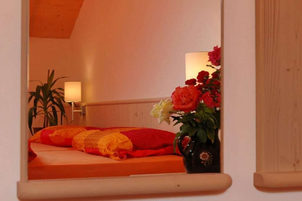 Ein Schlafzimmer mit einem Bett, einem Nachttisch, einer Lampe und einer Vase mit Blumen.