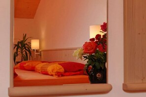 A bedroom with a bed, a bedside table, a lamp, and a vase with flowers. - Chardonnay - Santlhof (Kurtatsch)