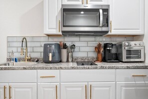 A kitchen with white cabinets, a stainless steel microwave, a coffee maker, and a toaster. - Chic 1-Bedroom Retreat - Phoenix (Phoenix)