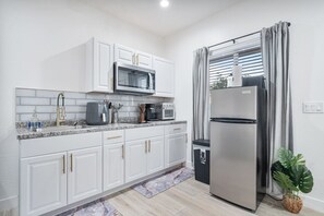 A modern kitchen with white cabinets, a stainless steel refrigerator, a microwave, and a coffee maker. - Chic 1-Bedroom Retreat - Phoenix (Phoenix)