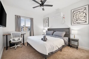 A hotel room with a bed, a desk, a chair, a ceiling fan, and artwork on the walls. - Chic 1-Bedroom Retreat - Phoenix (Phoenix)