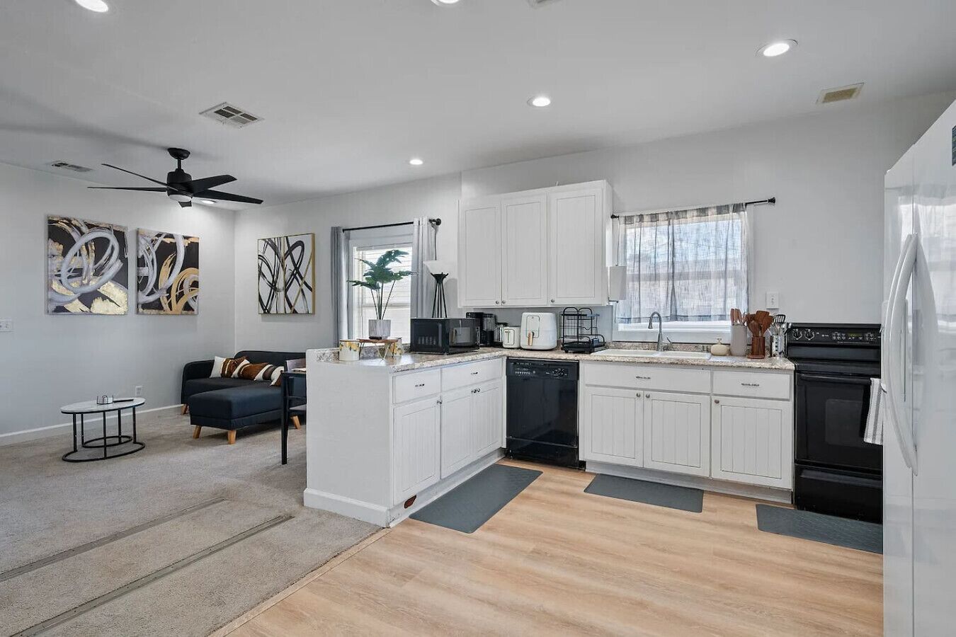 A modern kitchen with white cabinets, a black microwave, and a dishwasher.